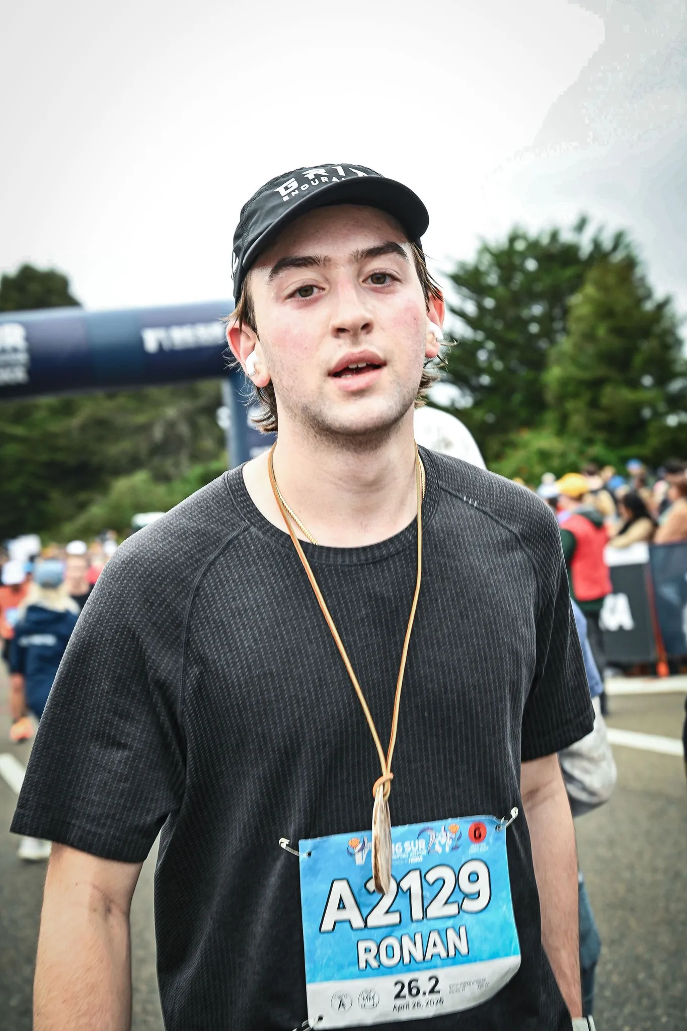 Ronan after the finish in a black cap and T-shirt with the finisher's medal around his neck and bib A2129 reading Ronan, 26.2.